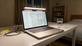 Lámpara LED Cenit enganchada encima de un portátil de noche, iluminando el teclado sin reflejos en la pantalla